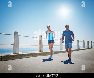 Persévérant ensemble. Un jeune couple sportif dehors pour une course ensemble. Banque D'Images