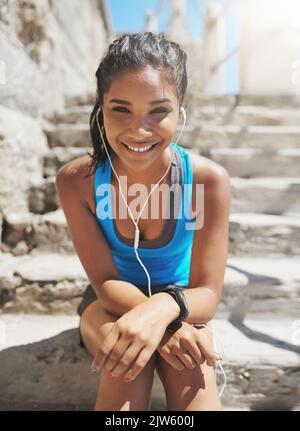 Il s'agit d'avoir la bonne attitude. Portrait d'une jeune femme sportive avec écouteurs. Banque D'Images