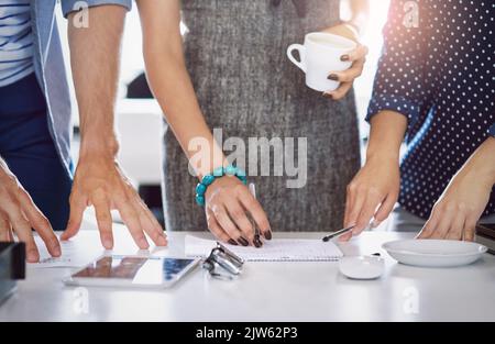 Mettre en place de grands projets. Gros plan d'un groupe de concepteurs non reconnaissables travaillant ensemble dans un bureau. Banque D'Images