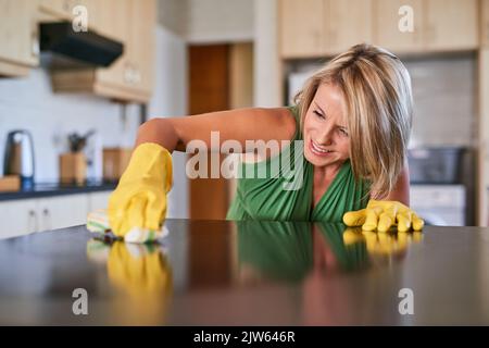 Se débarrasser des taches tenaces. Une jeune femme nettoyant une surface de cuisine. Banque D'Images