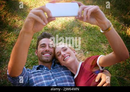 Souriant pour un selfie, un jeune couple affectueux qui profite d'une journée à l'extérieur. Banque D'Images
