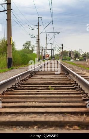 Le feu rouge est allumé. L'homme au loin marche le long des voies ferrées vers le train. Bruit de fond abstrait défoqué des chemins de fer en soirée. Banque D'Images