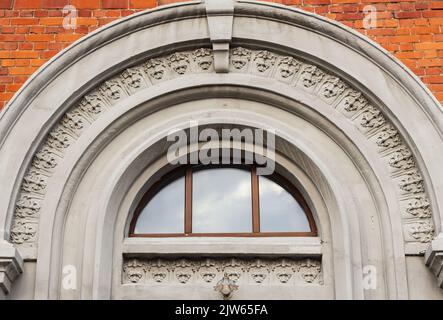 Fragment architectural de façade. Magnifique retwork en pierre de vieux bâtiment à Tomsk, en Russie. Ciel avec des nuages réfléchis dans la fenêtre. Lumière et merde Banque D'Images