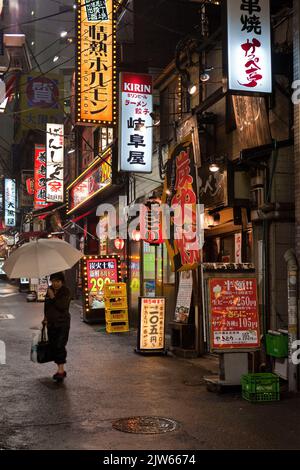 Restaurants des panneaux lumineux dans une rue pluvieuse la nuit à Shinjuku, Tokyo, Japon Banque D'Images