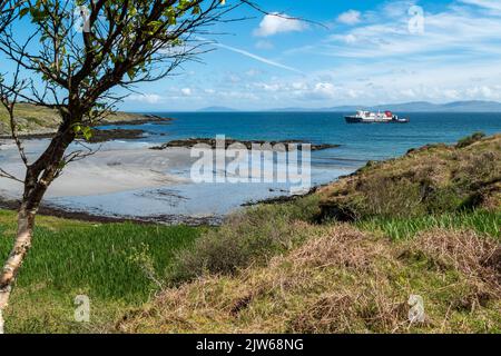 Le ferry calédonien MacBrayne 'Hebridean Isles' approche de l'île de Colonsay en route depuis Islay, avec une plage de sable de la Baie de la Reine en premier plan. Banque D'Images