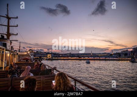 Istanbul, Turquie. 03rd septembre 2022. Les gens vus assis sur la terrasse des lignes de la ville ferry au coucher du soleil à Istanbul et le pont de Galata en arrière-plan avec les nuages ont créé une vue magnifique. Crédit : SOPA Images Limited/Alamy Live News Banque D'Images