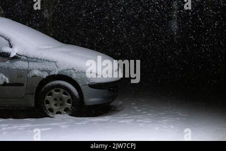 Varsovie, Pologne - 30 janvier 2021 : temps d'hiver avec chute de neige. Une voiture debout sous la lanterne la nuit, couverte de neige. Banque D'Images