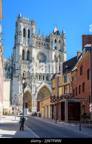 Façade gothique de la cathédrale notre-Dame d'Amiens vue d'une rue pavée en pente avec une vieille maison de ville à colombages par une belle journée d'été. Banque D'Images