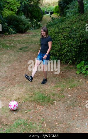 Jeune femme jouant au football dans le cadre du parc de campagne Banque D'Images