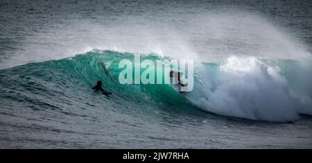 Les surfeurs ont capturé à cheval les meilleures vagues de Cornwall sur le récif de Porthleven. De magnifiques vagues turquoise s'élèvent au large du récif. Banque D'Images