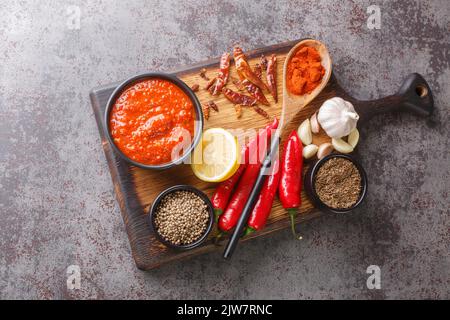 Pâte de sauce au piment fort harissa, cuisine arabe adjika sur le bol en bois avec les ingrédients de la ferme. Vue horizontale du dessus Banque D'Images