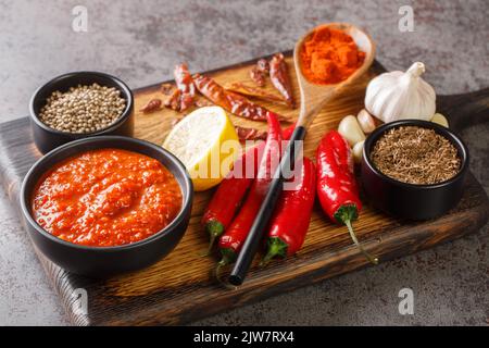Pâte traditionnelle maison de sauce au piment fort harissa avec de l'ail et de l'huile d'olive sur le bol en bois avec les ingrédients de la ferme. Horizontale Banque D'Images
