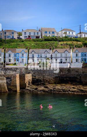 Terrasse avec vue sur la baie dans toute sa splendeur. Les vieilles maisons blanches de Porthleven sur le front du port avec deux flamants roses dans le port flottant par, Banque D'Images