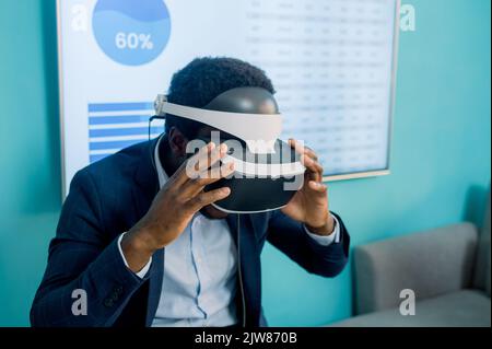 Homme d'affaires noir connaissant la réalité virtuelle dans un micro-casque moderne Banque D'Images