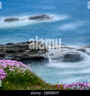 Une capture au ralenti des vagues qui s'écrasant sur les rochers au fond de la falaise de Porthleven. Banque D'Images