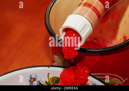 Une femme prépare du jus frais et sain à partir de tomates. Centrifugeuse au travail. Concept de régime alimentaire pour un mode de vie sain. Banque D'Images