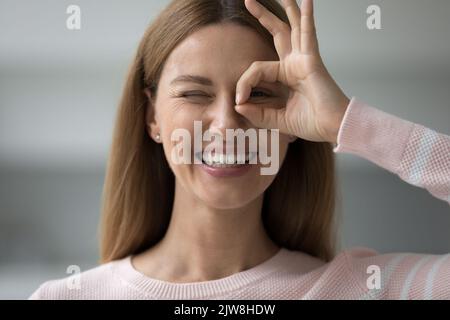 Gaie femme adulte regardant la caméra à travers main doigt binoculaire Banque D'Images