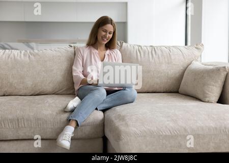 Joyeuse femme employée freelance utilisant l'application en ligne sur ordinateur portable Banque D'Images