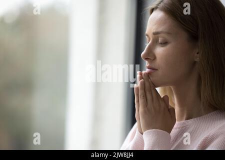 Sérieuse calme jolie femme adulte debout à l'intérieur de la fenêtre Banque D'Images