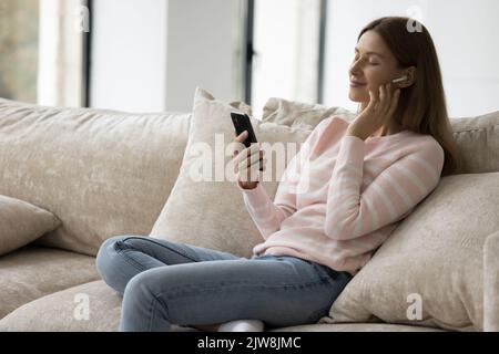 Paisible utilisateur de téléphone mobile se reposant sur un canapé avec les yeux fermés Banque D'Images