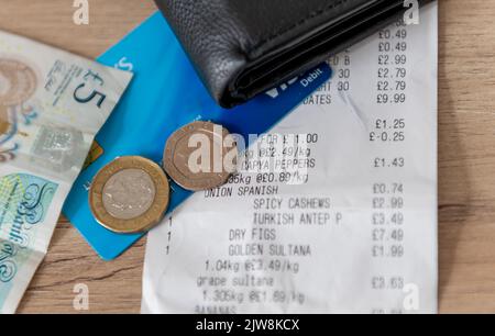 Un reçu de caisse, un sac à main, une carte bancaire et de l'argent comptant sur une table. Concept du coût de la vie. Banque D'Images