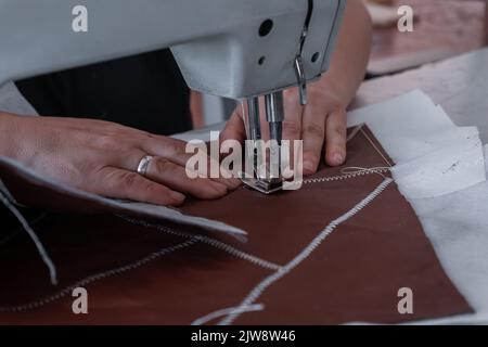 Les coutures de couturière à la machine à coudre filent le tissu. Mains des femmes Banque D'Images