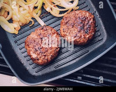 Cuisson du hamburger de bœuf haché sur une poêle à frire en fonte à l'extérieur, de la viande rouge sur une poêle à frire, de la nourriture grillée dans le jardin, concept de vie de campagne anglaise Banque D'Images