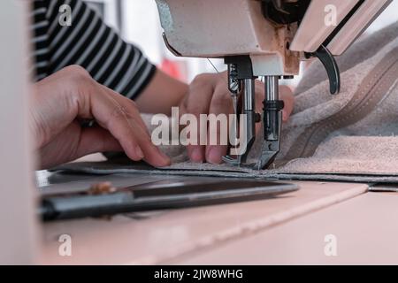 Les coutures de couturière à la machine à coudre filent le tissu. Mains des femmes Banque D'Images