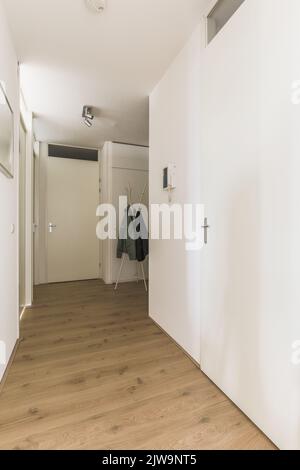 Couloir étroit et lumineux avec de nombreuses portes aux murs blancs. Banque D'Images