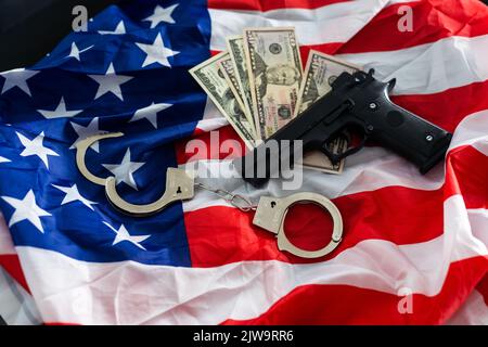 Arme à feu, étui, menottes et argent liquide devant le drapeau américain Banque D'Images