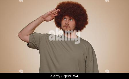 Oui, monsieur. Homme barbu subalterne, responsable, sérieux saluant écoutant l'ordre comme si soldat, suivant la discipline, obéissant, exprimant la confiance. Jeune garçon sur fond beige studio Banque D'Images