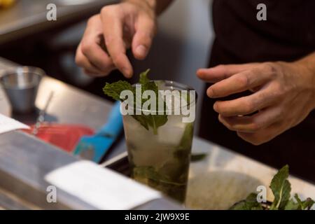 Barman préparant un cocktail. Préparation de cocktails dans un environnement nocturne. Il peut s'agir d'un hôtel, d'un restaurant ou d'une discothèque. Vie nocturne Banque D'Images