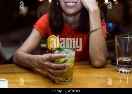 Femme au bar avec un cocktail à la main tout en appréciant une nuit de plaisir. Vie nocturne Banque D'Images