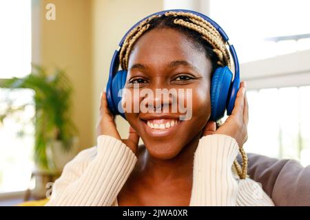 une femme latino-hispanique écoute de la musique tout en étant assise sur un canapé dans le salon Banque D'Images