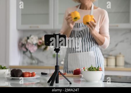 Cuisinez une femme blogueuse dans un tablier cuisant de la salade à la webcam Banque D'Images