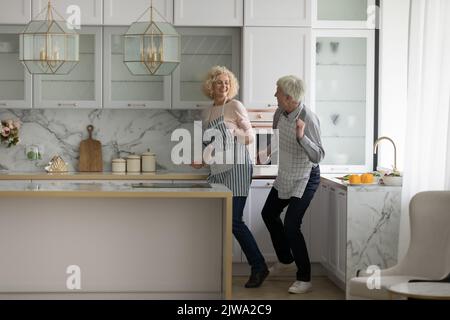 Heureux couple actif retraité portant des tabliers, apprenant la danse sociale Banque D'Images