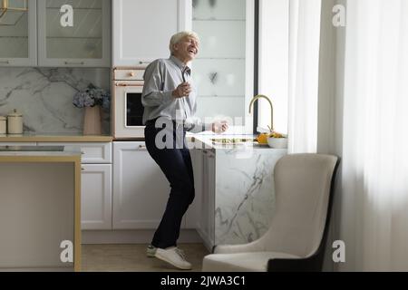 Homme senior plein d'énergie et enjoué dans une cuisine moderne Banque D'Images