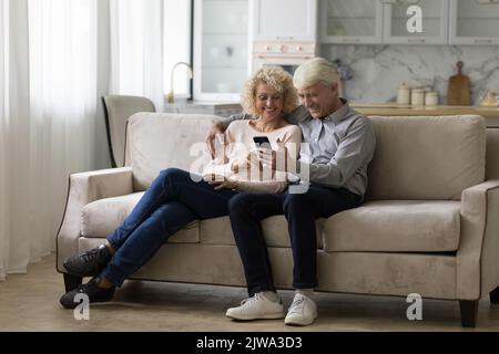 Heureux mari et femme senior joyeux utilisant un smartphone à la maison Banque D'Images