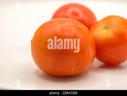 gros plan détaillé de trois tomates mûres étincelant Banque D'Images