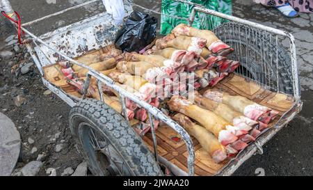 La vache s'accroche dans une brouette sur le marché alimentaire d'Osh, au Kirghizistan. La jambe de mouton crue est cuite et un repas aimé dans certains pays. Banque D'Images