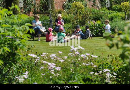 LES VISITEURS DE L'ABBAYE DE MOTTISFONT PRÈS DE ROMSEY HANTS, SE DÉTENDRE AU SOLEIL DANS LE JARDIN CLOS. PHOTO MIKE WALKER, 2013 PHOTOS DE MIKE WALKER Banque D'Images