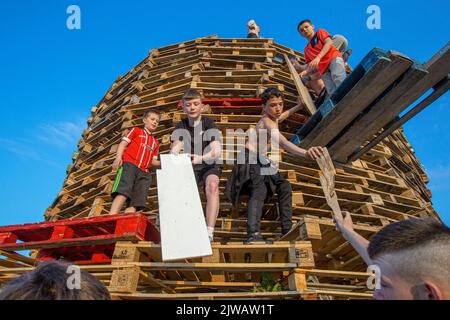 Les enfants empilent des palettes pendant le week-end en vue du feu de joie marquant un jour de fête catholique de l'Assomption de la Vierge Marie dans le ar de Bogside Banque D'Images