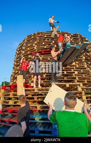 Les enfants empilent des palettes pendant le week-end en vue du feu de joie marquant un jour de fête catholique de l'Assomption de la Vierge Marie dans le Bogside Banque D'Images