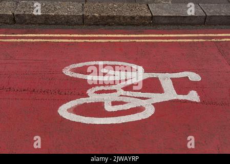 Plymouth, Devon, Angleterre, Royaume-Uni. 2022. Vélo peint en blanc sur une surface de route de couleur rouge le long d'une route de ville montrant un trottoir déroulant et une double ligne jaune Banque D'Images