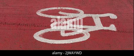 Plymouth, Devon, Angleterre, Royaume-Uni. 2022. Vélo peint en blanc sur une surface de route de couleur rouge le long d'une route de ville et d'un passage à vélo. Banque D'Images