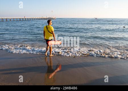 Maître nageur sur la plage méditerranéenne, observant les gens dans l'eau. Sécurité pendant la natation, beau brunette homme maître nageur sur la plage. Banque D'Images