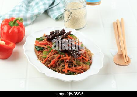 Japchae ou CHAP Chae, plat de nouilles en verre coréen avec bulgogi de bœuf et garniture de graines de sésame Banque D'Images