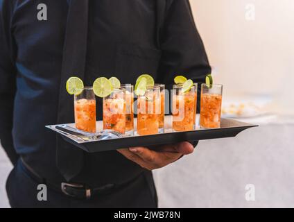 Serveur non reconnaissable habillé de noir avec un plateau de sandwiches cocktail de crevettes avec espace de copie Banque D'Images