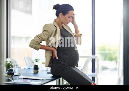 Son congé ne peut pas venir assez vite. Une femme d'affaires enceinte dans l'inconfort dans son bureau. Banque D'Images
