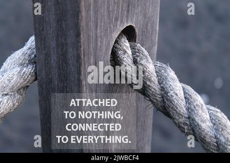 Citation motivationnelle inspirante - jointe à rien, connectée à tout. Avec corde naturelle connectée sur un trou de clôture en bois de couleur grise. Banque D'Images